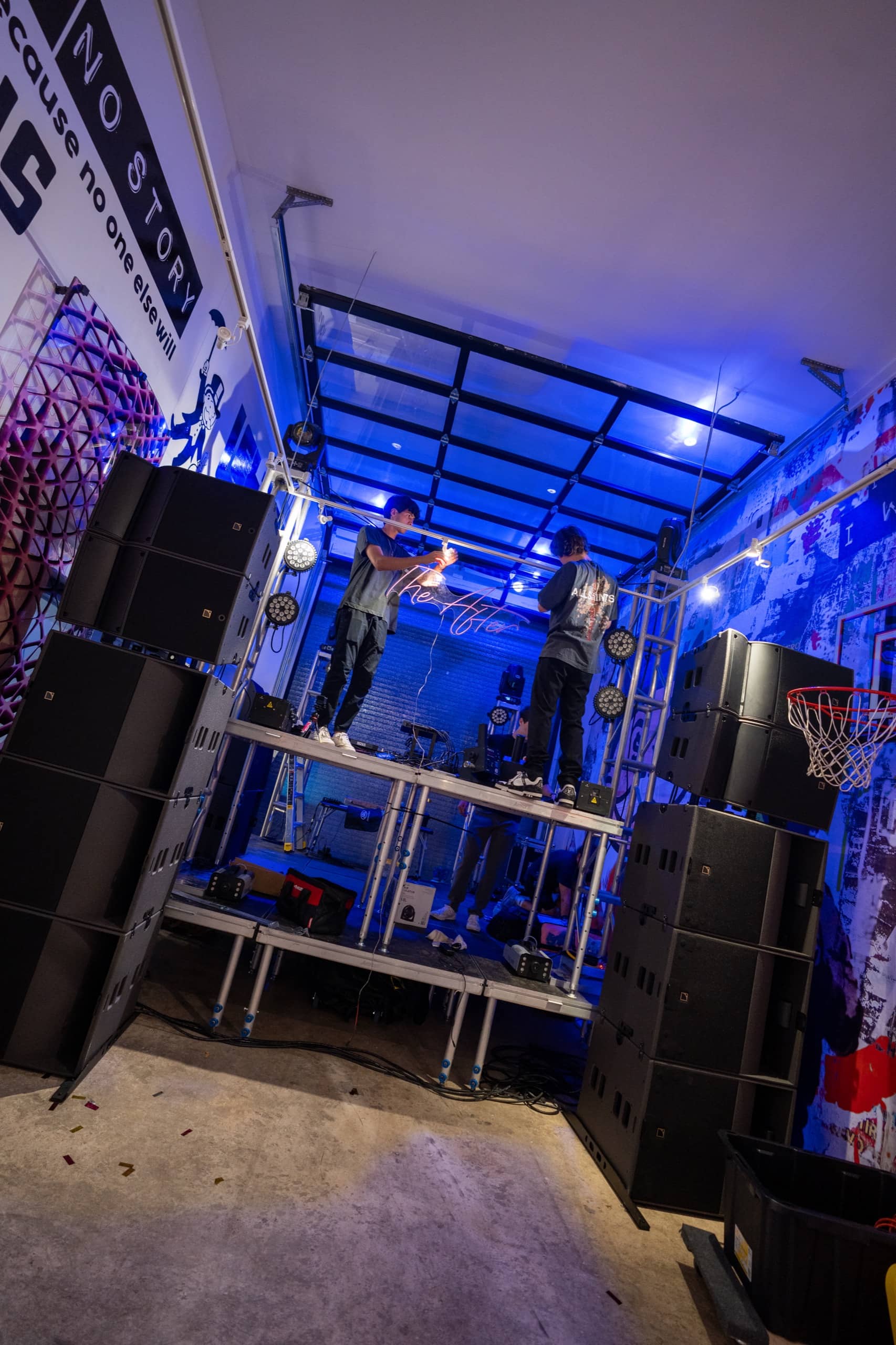 The build: crew assembling stage decks and speaker towers under blue work light