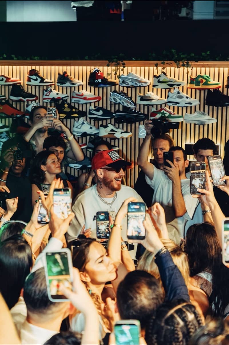 HUGEL in the middle of a crowded sneaker showroom, everyone filming with raised phones