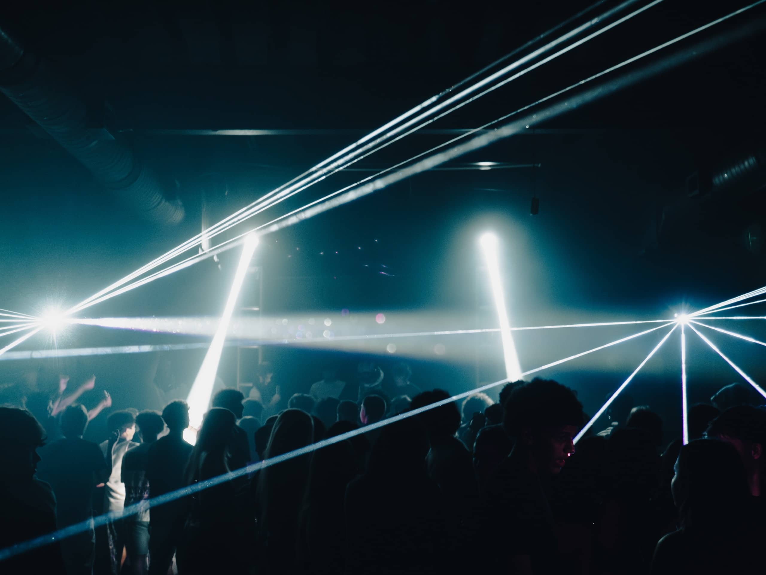 White laser beams crossing over a club crowd in haze