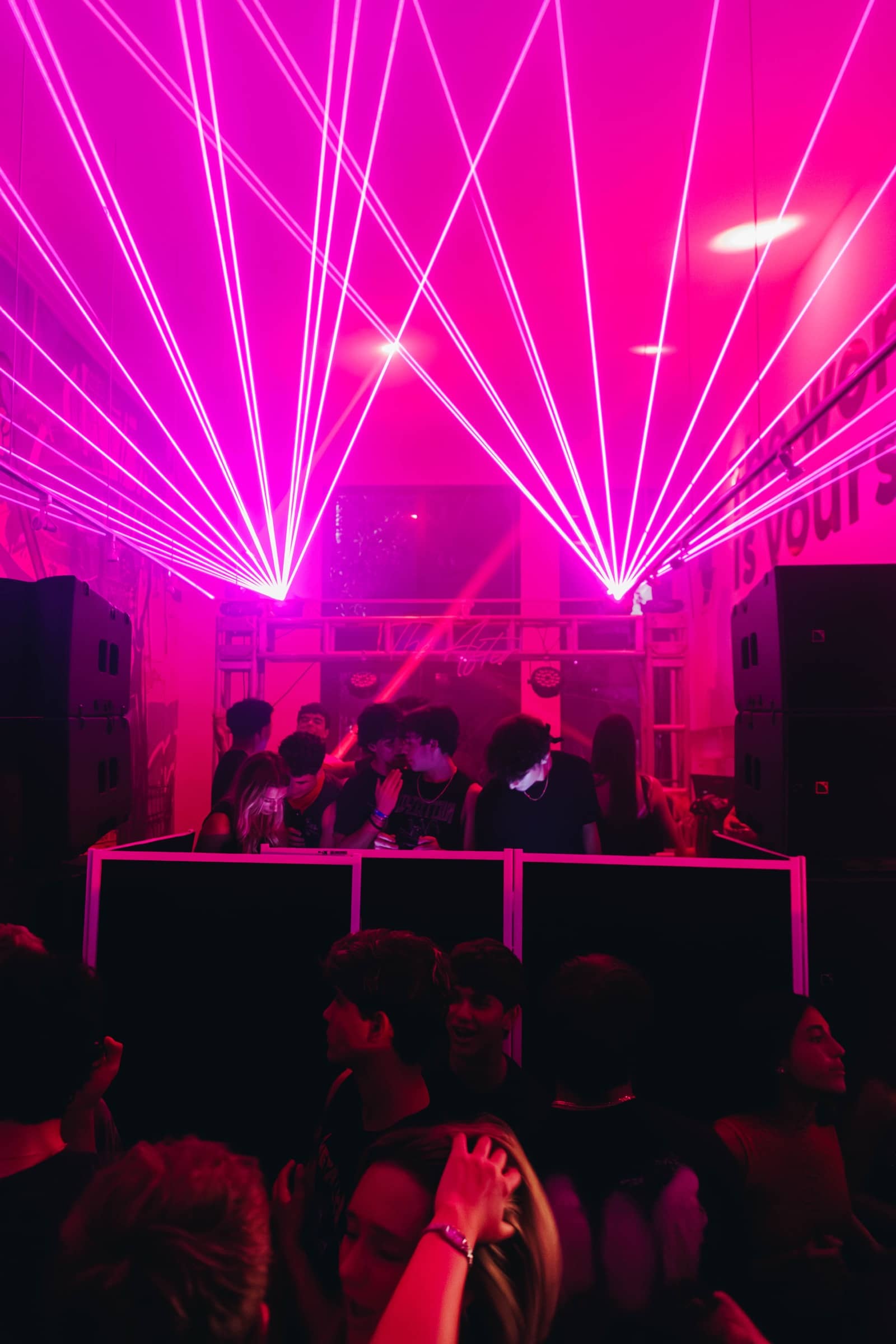 Magenta laser fans spreading over the DJ booth