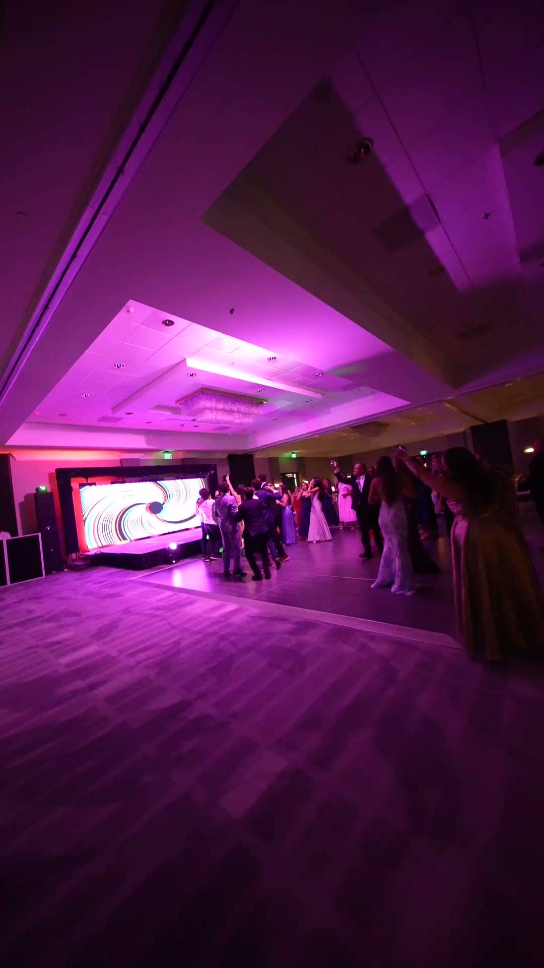 Gala guests on a purple-lit ballroom floor in front of the LED wall