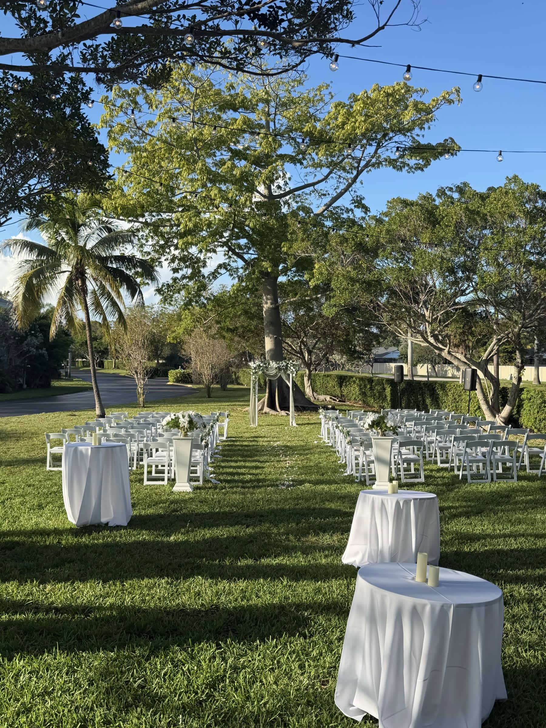 Outdoor wedding ceremony set on a lawn under string lights
